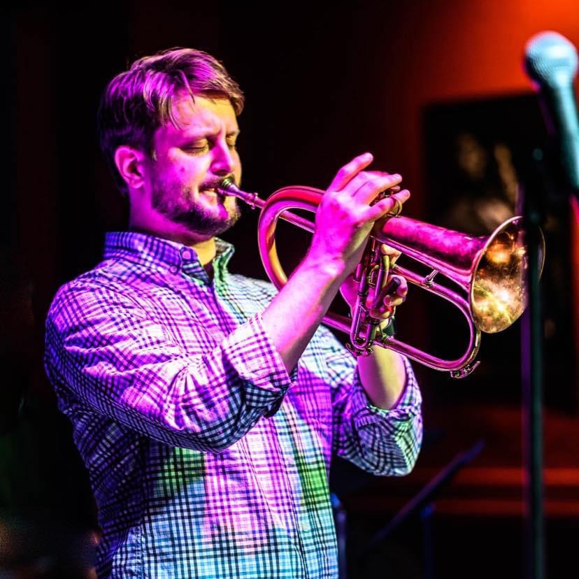 A color photograph of David Moore playing a horn