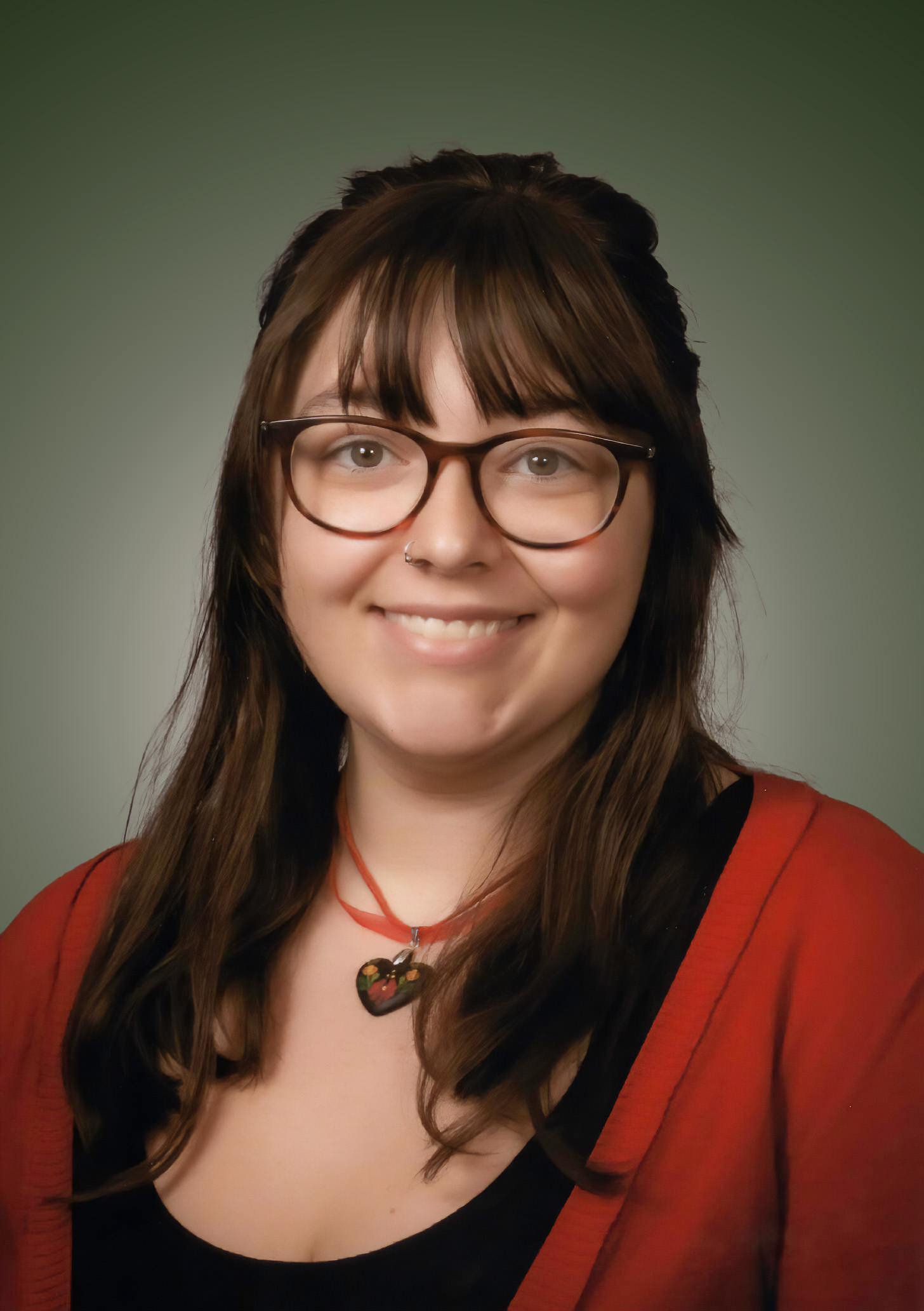 A color photo of ISABELLA SZABO smiling. She has brown hair with bangs, glasses, and a red cardigan.