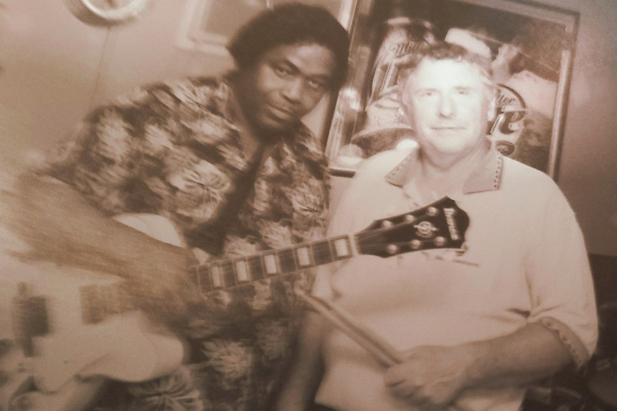 Sepia toned photo of Stone Cold Blues Band members posing with a guitar