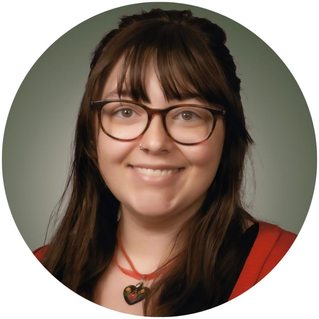 A color photo of BELLA SZABO smiling. She has brown hair with bangs, glasses, and a red cardigan.