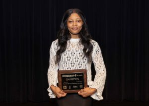 young woman smiling holding an award