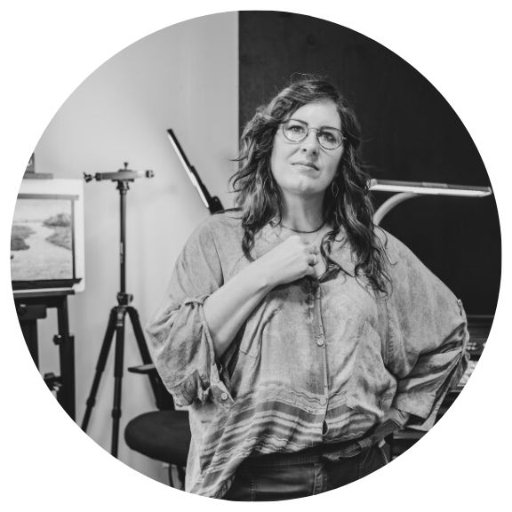 Woman standing in front of art in a studio.