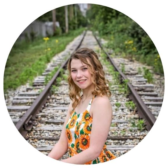 Woman smiling in front of train tracks.