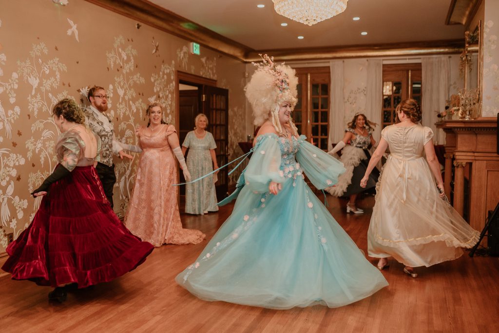 A group of people dancing dressed in regency-inspired attire.