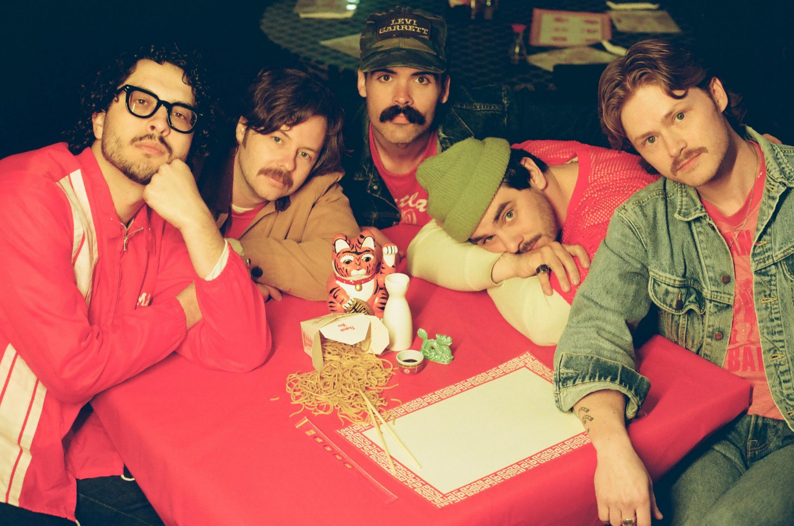 group of 5 sitting at a restaurant table with takeout