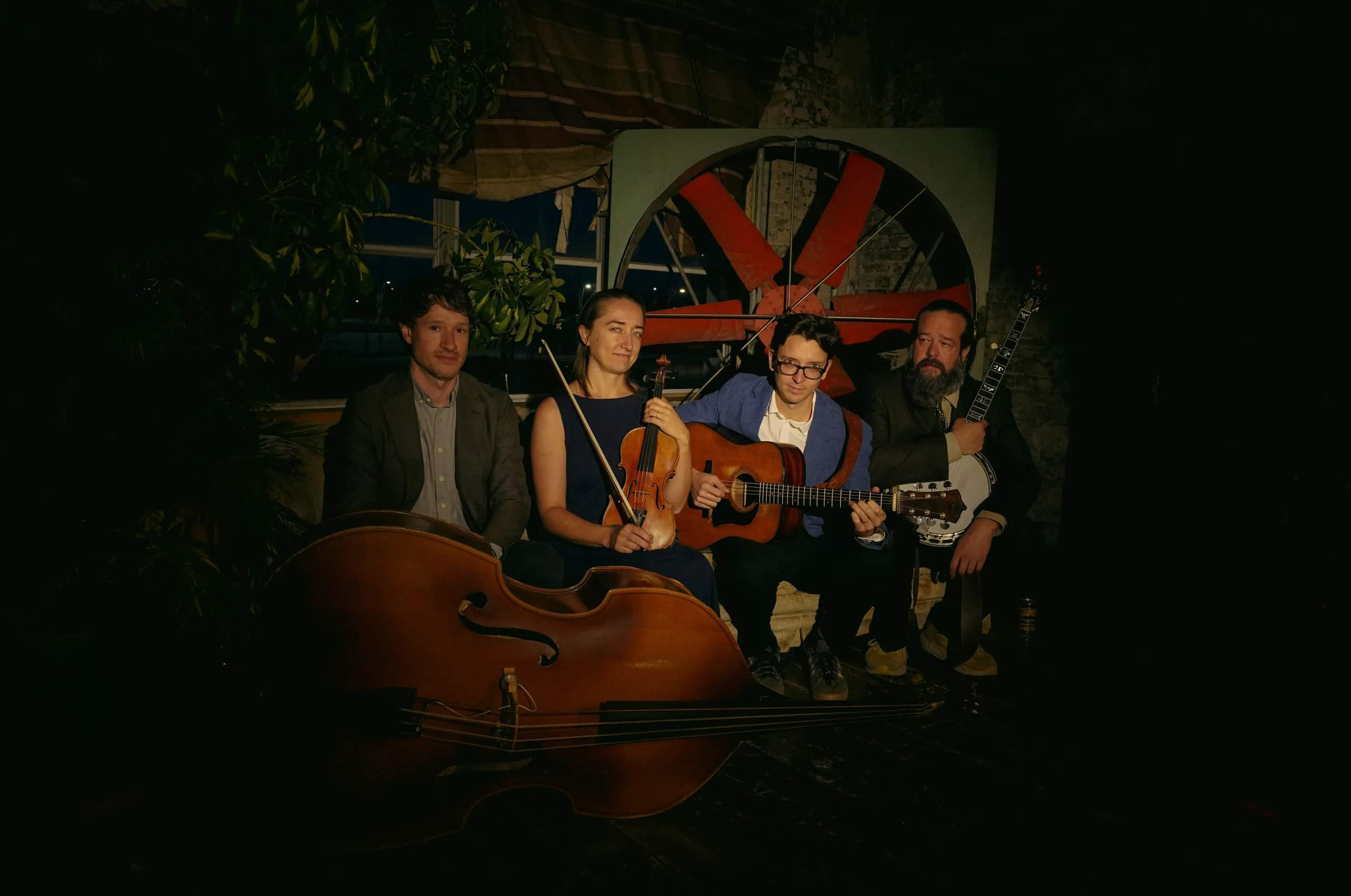 band of 4 musicians sitting together and holding instruments