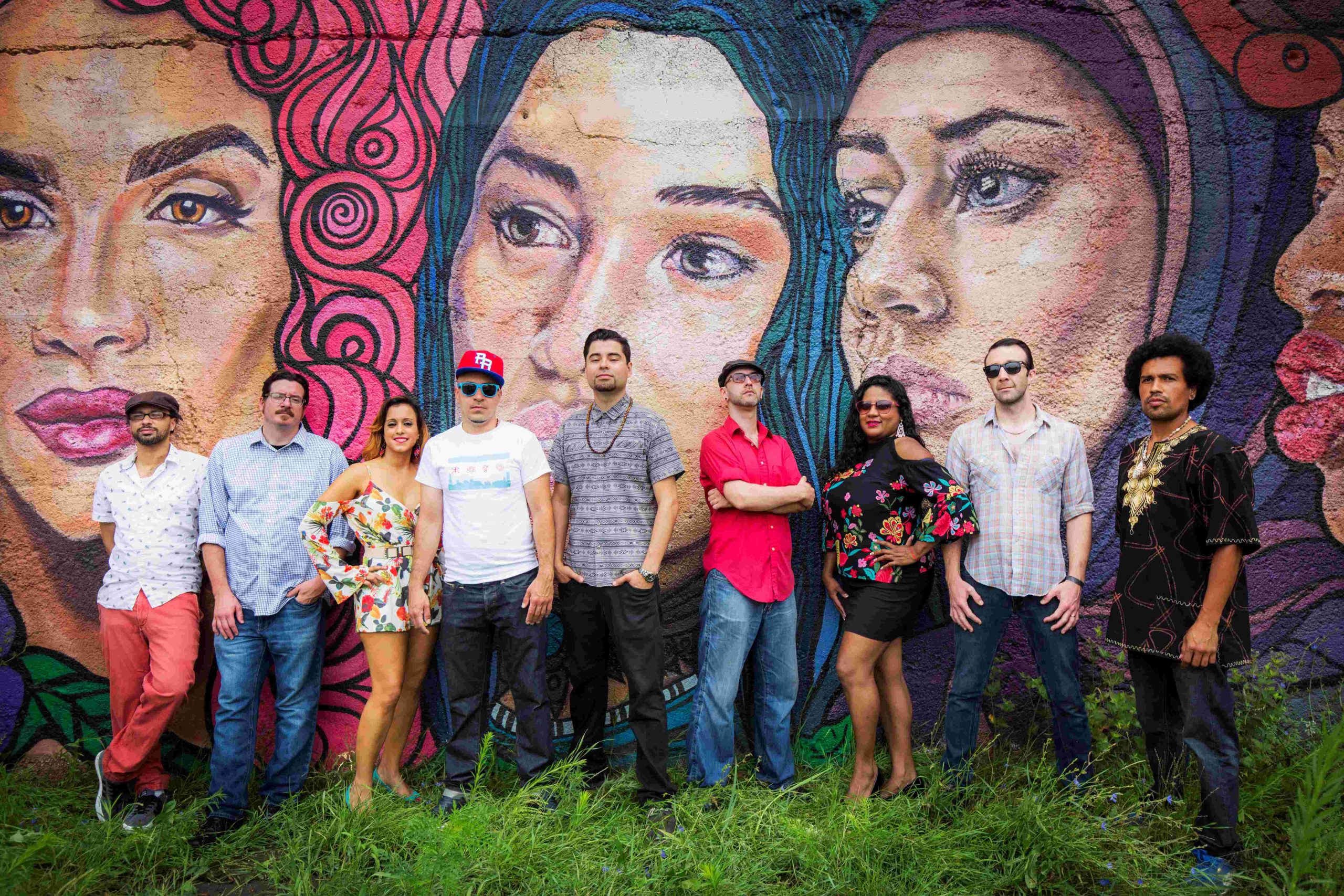 group of 7 people posing together outside in front of a mural