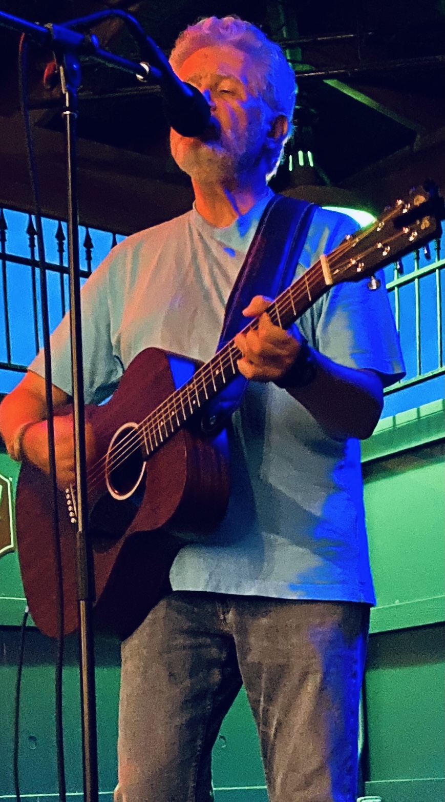 Man singing on stage playing guitar.