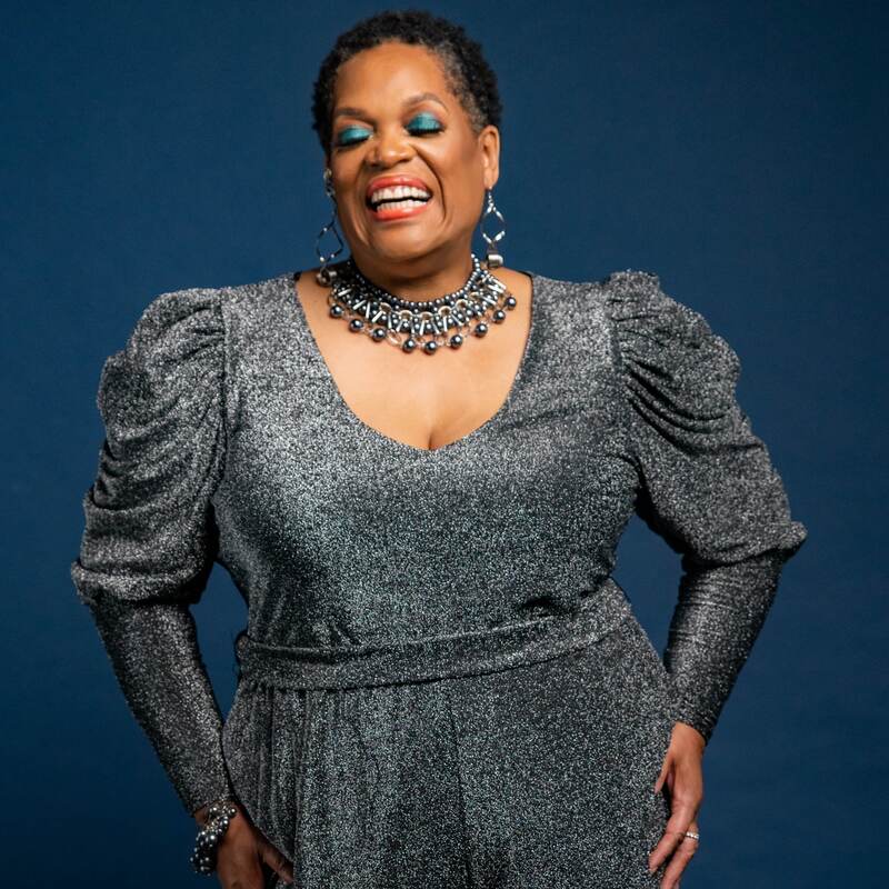woman wearing elegant dress with jewelry, laughing at the camera