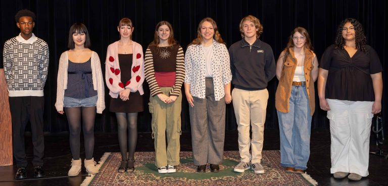 Group of 8 student contestants posing on stage