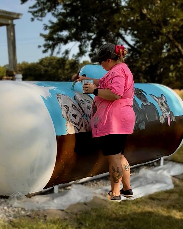 Woman painting mural on septic tank