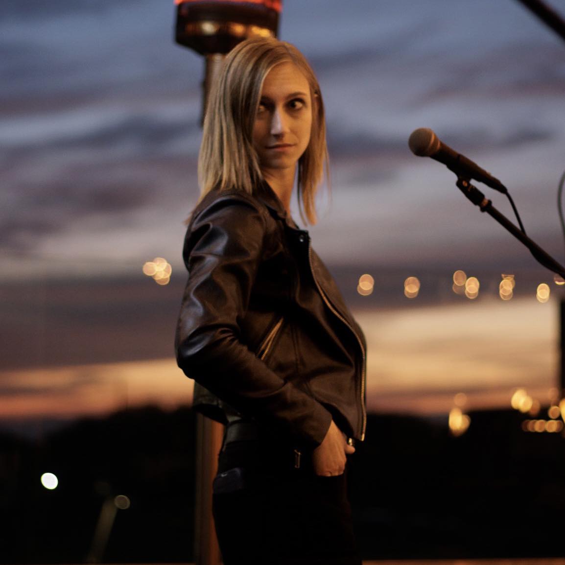 Woman on outdoor stage posing in front of microphone